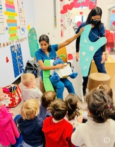 two dental professionals teaching a classroom of children about oral health