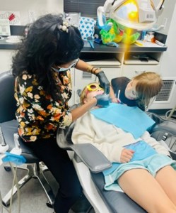 Young patient during her dental exam with two dental professionals assisting